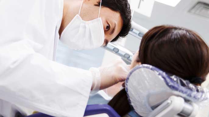インプラント治療後の定期ケアを男性歯科医師に行ってもらってる女性
