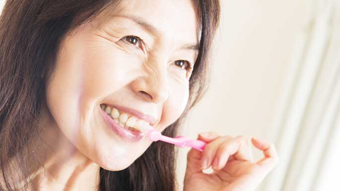 インプラント治療後に自宅で歯磨きをしてる女性